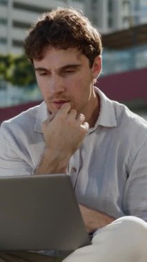 Düşünceli, güler yüzlü beyaz iş adamı dizüstü bilgisayarlı iş adamına bakıyor. Güler yüzlü, güler yüzlü bir iş adamı. Şehirdeki internet sitesiyle uzaktan çalışan işveren.