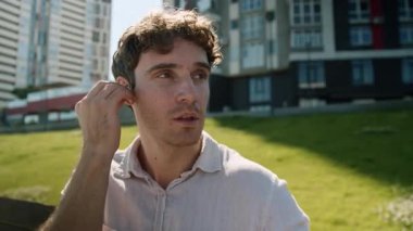 Kafkasyalı iş adamı kablosuz kulaklık takıyor. Şehir bankında dinleniyor. Huzurlu iş adamı kulaklıklarıyla müzik dinliyor.