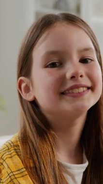 Kaygısız, gülümseyen, beyaz, sevimli küçük kız kameraya bakıyor dişlek, sağlıklı dişli, neşeli, mutlu kız çocuğu evde poz veriyor oturma odasında evlat edinme aile çocuk sağlığı hizmetlerinde.