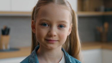 Ev mutfağındaki yakın plan portre beyaz kız mutlu bir şekilde gülümsüyor ev ortamındaki neşeli vesikalıklara bakıyor çocuk gülüşü çocuk oyuncağı konsepti benimsiyor