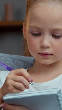 Kafkas odaklı küçük kız çocuğu ev ödevi yapıyor ilköğretim öğrenimi hazırlık sınavları okuyor not defterine sevimli öğrenci kız öğrenci eğitim kitabı yazıyor.