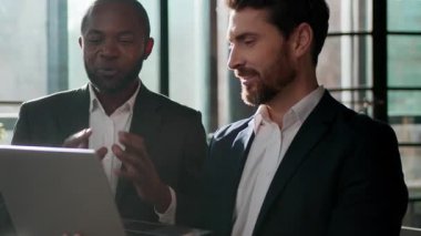 İki gülümseyen adam iş adamları laptoplu iş adamları bilgisayar beyaz iş adamı ile keyifli bir iletişim çalışması yapıyor. Fikir danışmanı Afrikalı Amerikalı lider