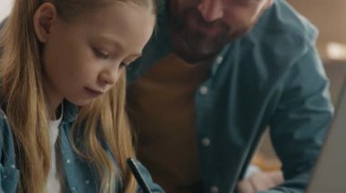 Beyaz bir baba, sevimli kızına yardım ediyor. Mutfak masasında evde öğrenim görüyor. Sevgi dolu bir baba.
