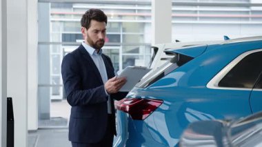 Kafkasyalı iş adamı okuma sözleşmesi ile galeri içinden yeni bir araba satın aldı. Galeri erkek alıcısı. Evrakları analiz ediyor.