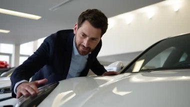 Beyaz iş adamının yeni araba galerisini seçmesine sevindim. Kucaklaşan araba lambası, gülümseyen alıcı, müşteri, galeri, sarılma, araba rüyası, araba şoförü, otomobil nakliye salonu.