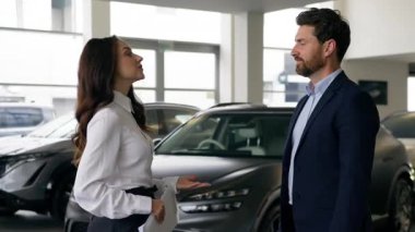 Kafkas kadın satıcı araba galerisi danışmanı müşteri danışmanı el sıkışıyor iş kadını kadın işkadını kadın oto galerisi konuşan iş adamı el sıkışarak araba kiralama satın alıyor.