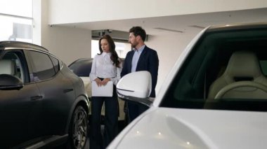 Beyaz erkek müşteri yeni araba seçiyor kadın danışman galeri simsarı ile iletişim kuruyor otomobil kuaföründe ticaret yürüyüşüne danışmanlık yapıyor kadın düşüncesiyle oto kiralama servisi yapan erkeği seçiyor.