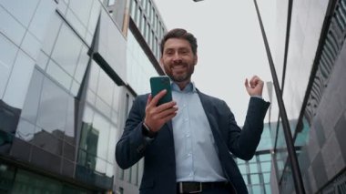 Mutlu Kafkasyalı yetişkin iş adamı cep telefonu başarısını şehir orta yaşlı iş adamı heyecanlı girişimci adam menajer zaferi kazandı nakit para ödülü kazandı