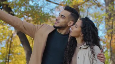 Güler yüzlü İspanyol çift güler yüzlü sonbahar parkında altın yapraklı yapraklı yapraklar hakkında konuşur şehirde mutlu bir kadın, sarılır, sarılır, sarılır, sarılır, sarılır, sarılır Arap ailesini sever