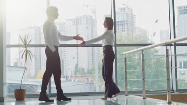 İki Kafkasyalı iş arkadaşı şirket salonunda tokalaşırken başarılı iş adamı ve iş kadını tokalaşırken ofis içi selamlaşmaları müzakere görüşmeleri işbirliği takım çalışması hakkında konuşuyorlar.