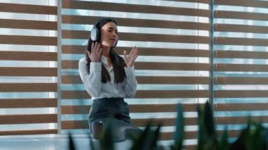 Kafkasyalı rahat Kafkas iş kadını kulaklıkla müzik dinliyor bateri çalıyormuş gibi yapıyor iş kadını kulaklıklarıyla şarkı söylüyor ofiste dinleniyor neşeli bayan menajer sesi seviyor