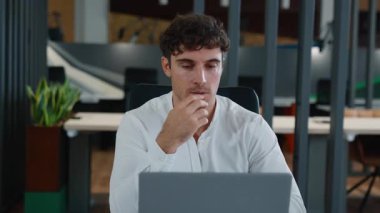 Odaklanmış Kafkasyalı iş adamı bilgisayarlı, bilgisayar odaklı bir iş adamı olarak bilgisayarlı, kararsız, tereddütlü bir ajanın ofiste çalışmasını düşünüyor.