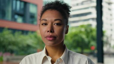 Fotoğraftaki Afrikalı Amerikalı iş kadını kameraya bakıyor. Şehirde sakin bir şekilde gülümsüyor. İş kadını kadın.