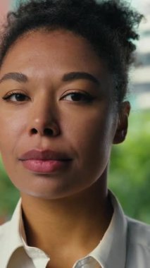 Fotoğraftaki Afrikalı Amerikalı iş kadını kameraya bakıyor. Şehirde sakin bir şekilde gülümsüyor. İş kadını kadın.