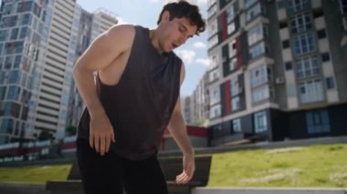 Beyaz tenli sporcu erkek koşuyor. Mola veriyor. Mola veriyor, nefes alıyor. Terli alnını siliyor.