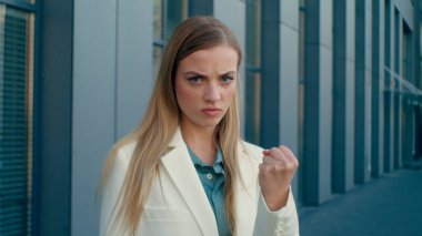 Kızgın, kızgın, Kafkasyalı iş kadını. Yumruk sallama tehdidi. Dışarıdaki kameraya bakıyor. Tatminsiz bayan iş kadını.