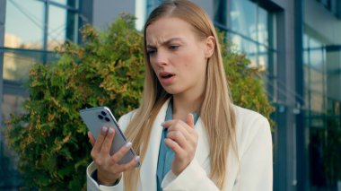 Şok olmuş Kafkasyalı iş kadını cep telefonuyla kötü haberler yazıyor açık havada hayal kırıklığına uğramış kız lider SMS alıyor iş kadını şirketi iflas ile karşı karşıya sokak başarısızlığı
