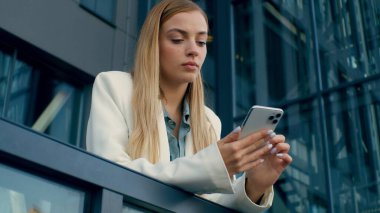 Hüsrana uğramış Kafkasyalı iş kadını şehir dışındaki balkonda cep telefonunu kontrol ediyor. Kadın lider iş kadını, üzgün işçiye bakıyor. Kötü haber mesajları, para sıkıntısı, anksiyete sorunu.