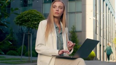 Düşünceli Kafkasyalı iş kadını dışarıda dizüstü bilgisayarda yazı yazıyor. Düşünceli kadın iş kadını gazeteci. Uzaktan kumandalı online yazım planı üzerinde çalışıyor.