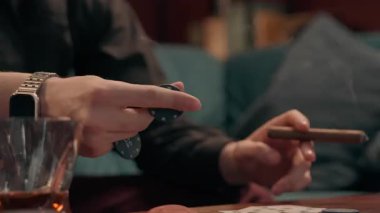 Tanımlanamayan beyaz adam, kumarbaz, puro içen, sigara içen erkek, poker fişi çeviren, kumar oynayan, evde alkol içen, sağlıksız yaşam tarzı bağımlısı.