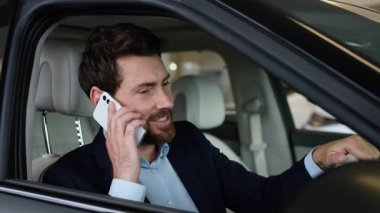 Mutlu Kafkasyalı iş adamı akıllı telefon galerisi konuşuyor. Yeni arabanın içinde oturmuş gülüyor. İş adamı cep telefonuyla konuşuyor.