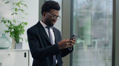 Afro-Amerikalı işadamı hayal kırıklığına uğramış cep telefonunu rahatsız eden, sohbet eden akıllı telefon iş adamı cep telefonu tutan, elinde negatif haber arızası olan bir adam.