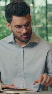 Hintli iş adamı Arap işadamı kafede notlar yazıyor. Kötü haberler alıyor. Cep telefonuyla konuşuyor.