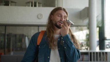 Sinirli, Kafkasyalı, erkek öğrenci, sesli mesaj kaydediyor. Sesli mesaj kaydediyor. Akıllı telefon kullanarak cep telefonuna dikte ettiriyor.