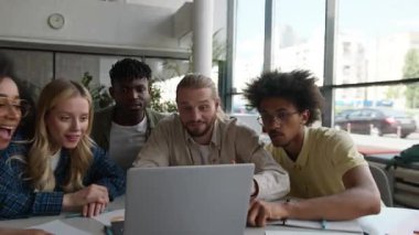 Beş mutlu çok ırklı sınıf arkadaşı online dizüstü bilgisayar okuyarak iyi haberleri kutluyor başarılı tepki çeşitliliği arkadaşlarıyla üniversite kampüsünde e-öğrenim yapan bilgisayarlı arkadaşlar bağırıyor.