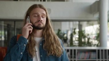 Cep telefonundan konuşan ciddi bir negatif beyaz adam kötü haberler alıyor. Erkek öğrenci konuşmaları, akıllı telefon konuşmaları üniversite üniversitesinde sorunlu konuşmalar.