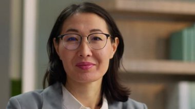 Orta yaşlı, dizüstü bilgisayarlı, gülümseyen Asyalı iş kadını, gülümseyen Koreli iş kadını, gülümseyen, neşeli bir portre çizen Çinli kadın girişimci, ofiste çalışan gözlüklü.