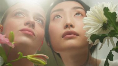 Parlak güneş ışığına bakan iki farklı kadın. Kapalı alanda çiçek açan Asyalı beyaz kızlar. Hayalperest kadınlar.