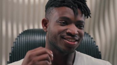 Neşeli Afrikalı Amerikalı adam, kablosuz kulaklık takıyor, gülümsüyor, fütüristik uzay tebessümiyle müzik dinliyor, dinleniyor, erkek adam, modern fütürizm kulaklıkları kullanıyor, müzik dinliyor.