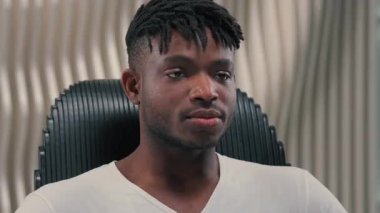 Portre yüzü fütüristik kendine güvenen ciddi oyun programcısı fütürizm modern beyaz oda stüdyosunda erkek Afrikalı Amerikalı adam göz kırpan göz kırpma teknolojisine bakıyor.