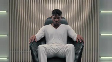 Futuristik kendine güvenen ciddi oyun programcısı Afrikalı Amerikalı erkek adam koltukta oturan fütürizm modern oda stüdyosu koltukta 3D bilgisayar grafikleri ve yapay zeka ağı konseptine bakıyor.