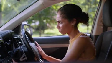 Kızgın Afrikalı kadın şehirde bozuk araba çalıştırmaya çalışıyor. Şoför işe geç kaldı. Otomobil kontağı bozuldu.