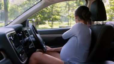 Hamile Afro-Amerikalı kadın emniyet kemerini bağlıyor. Araba şehrinde kadın sürücü. Anne, koruma otomobili taşımacılığı, hamilelik, sağlık hizmetleri.