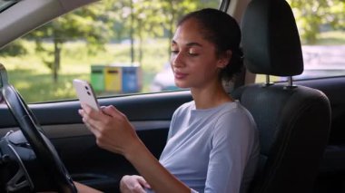 Hamile Afro-Amerikan kadın anne gülümsüyor. Cep telefonu kullanıyor. Araba sürücüsü gelecekteki anne cep telefonuna bakıyor.