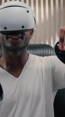 Mutlu Afrikalı Amerikalı adam sanal gerçeklik oyunu oynuyor. Elinde oyun kağıtları var. Fütüristik odada koltukta oturuyor. Fütürizm siber uzay adamı erkek.