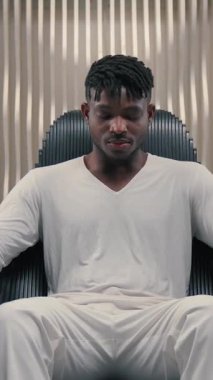 Fütürizm Afrikalı Amerikalı bir adam, parmaklarını bir jest gibi gösterip fütüristik uzayda oturmuş mutlu bir şekilde gülümsüyor.