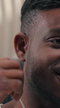 Afro-Amerikalı gülümseyen siber adam, kablo kulaklık takıyor, müzik dinliyor, boş zamanın tadını çıkarıyor. Kapalı mekanlarda dinleniyor, erkek erkeğe gülümsüyor, kulaklık takıyor.