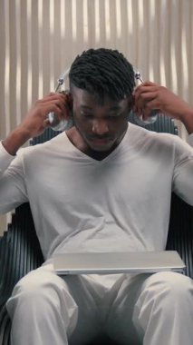 Yoğunlaşmış Afrikalı Amerikalı erkek kulaklık takıyor, dizüstü bilgisayar açıyor yenilikçi siber uzay teknolojisi yazışıyor, modern bilgisayar yazılımı fütüristik oda oyunu bağımlılığı online fütürizm.