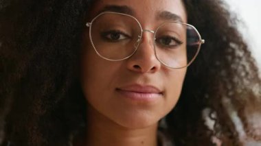 Afro-Amerikalı etnik kız öğrenci iş kadını bayan müşteri kameraya bakıyor kıvırcık saçlı, gözlüklü, gözlüklü, görüş sorunu olan, sağlık eğitimi alan, iş kadını.
