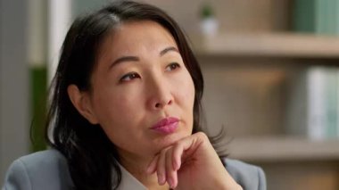 Düşünceli, düşünceli, Asyalı iş kadını Çinli, Koreli, Japon, derin düşüncelere dalan, derin düşüncelere dalan, sorunlu, iş kadını şüphesiyle yaklaşan, ofiste beyin fırtınası analizi yapmayı düşünen bir kadın.