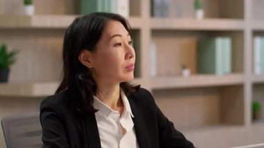 Çinli iş kadını Asyalı kız Koreli iş adamı Japon kadın patron yönetici yönetici komisyoncu ofis masasında çalışıyor orta yaşlı kadın portresi mutlu gülümseyen bayan