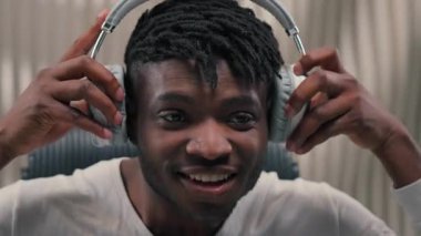 Kapat mutlu Afrikalı Amerikalı adam kulaklık tak müzik dinle enerjik dans et fütüristik odada erkek adam gülümse eğlence özgürlük şarkı söyle dans et siber uygulamanın tadını çıkar