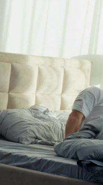 Kafkasyalı bir adam yatağında uzanıyor. Sabah uykusunda, yatak odasında uyanıyor. Rahat bir şekilde gözlerini ovalıyor.