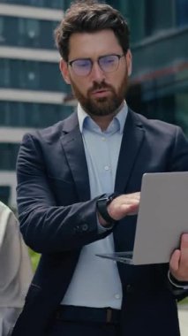 Şehirde dizüstü bilgisayarda çalışan çok ırklı iş ortakları Kafkasyalı iş adamı Afrikalı iş kadını erkek iş arkadaşları açık hava bilgisayar planlama projesini kullanan kadın işadamları hakkında tartışıyorlar.