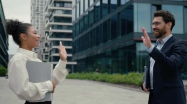 Happy multiethnic business colleagues high five greeting in city meeting outdoors discussing startup African businesswoman Caucasian businessman smile talking idea teamwork collaboration entrepreneurs