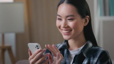 Asyalı Koreli kadın blogcu, cep telefonuna bakıp gülümsüyor. İnternet üzerinden mesajları kontrol ediyor. Akıllı telefon alışveriş uygulaması kullanıyor.